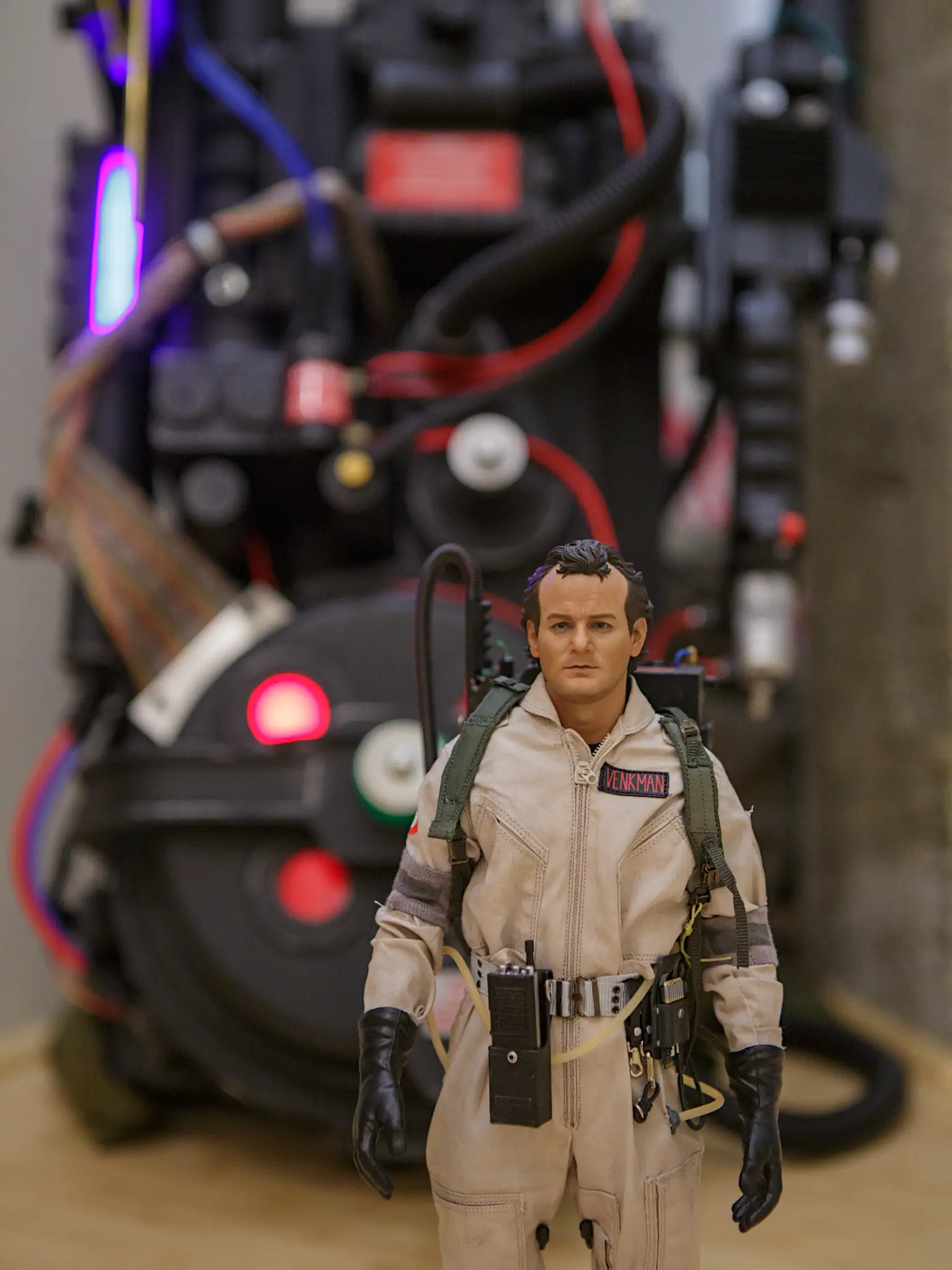 Blitzway 'Venkman 1984' scale Ghostbusters figurine, with a full-size proton pack in the background.